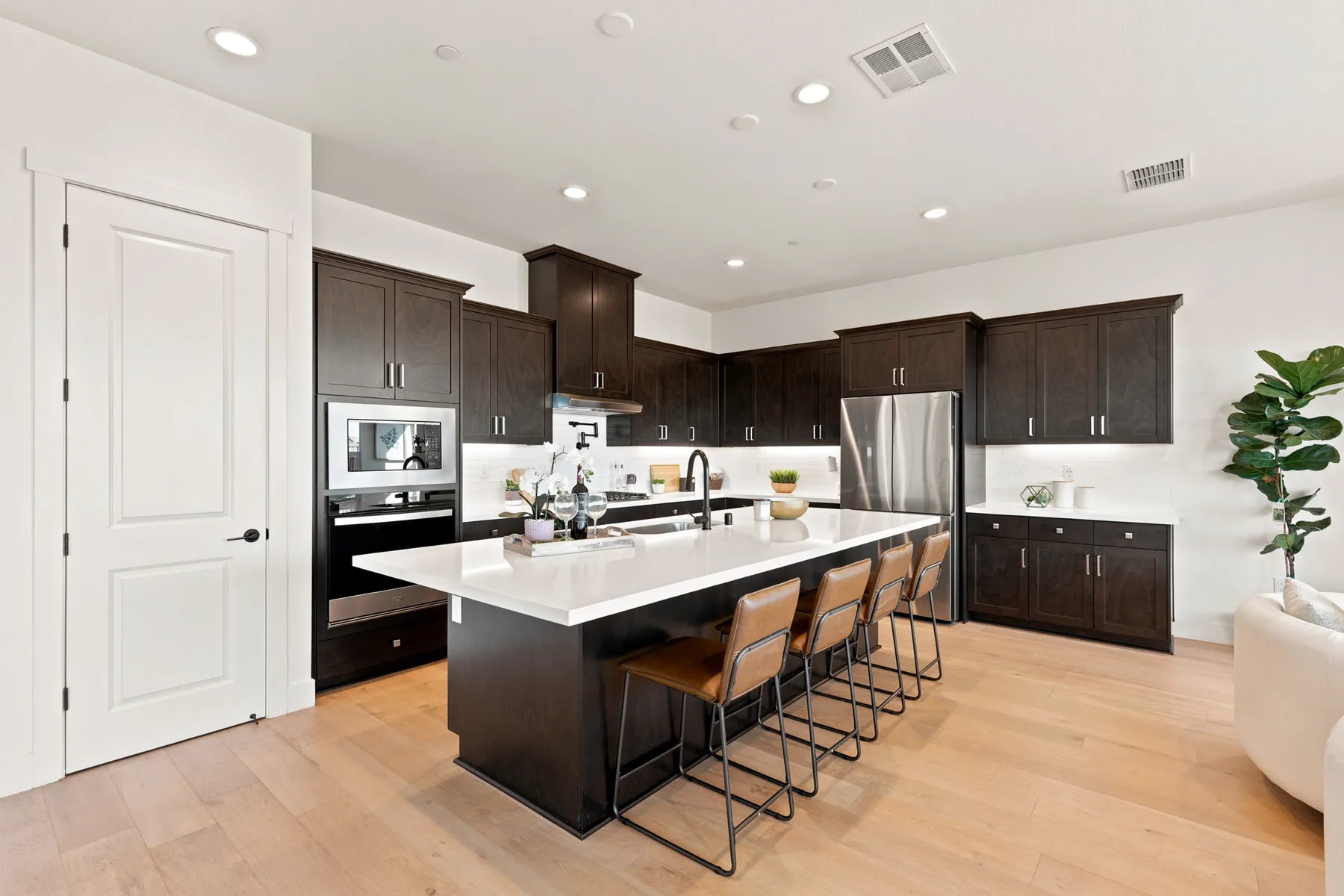 Kitchen with dark cabinets, a white island, and bar seating.